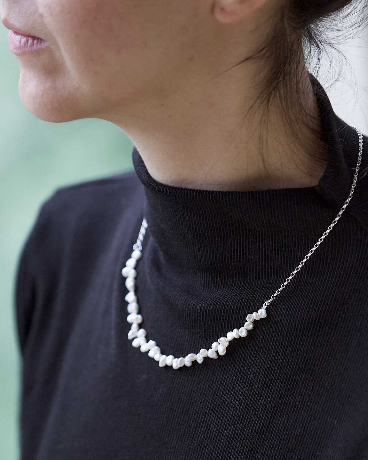 Person wearing a pearl necklace with a blurred background
