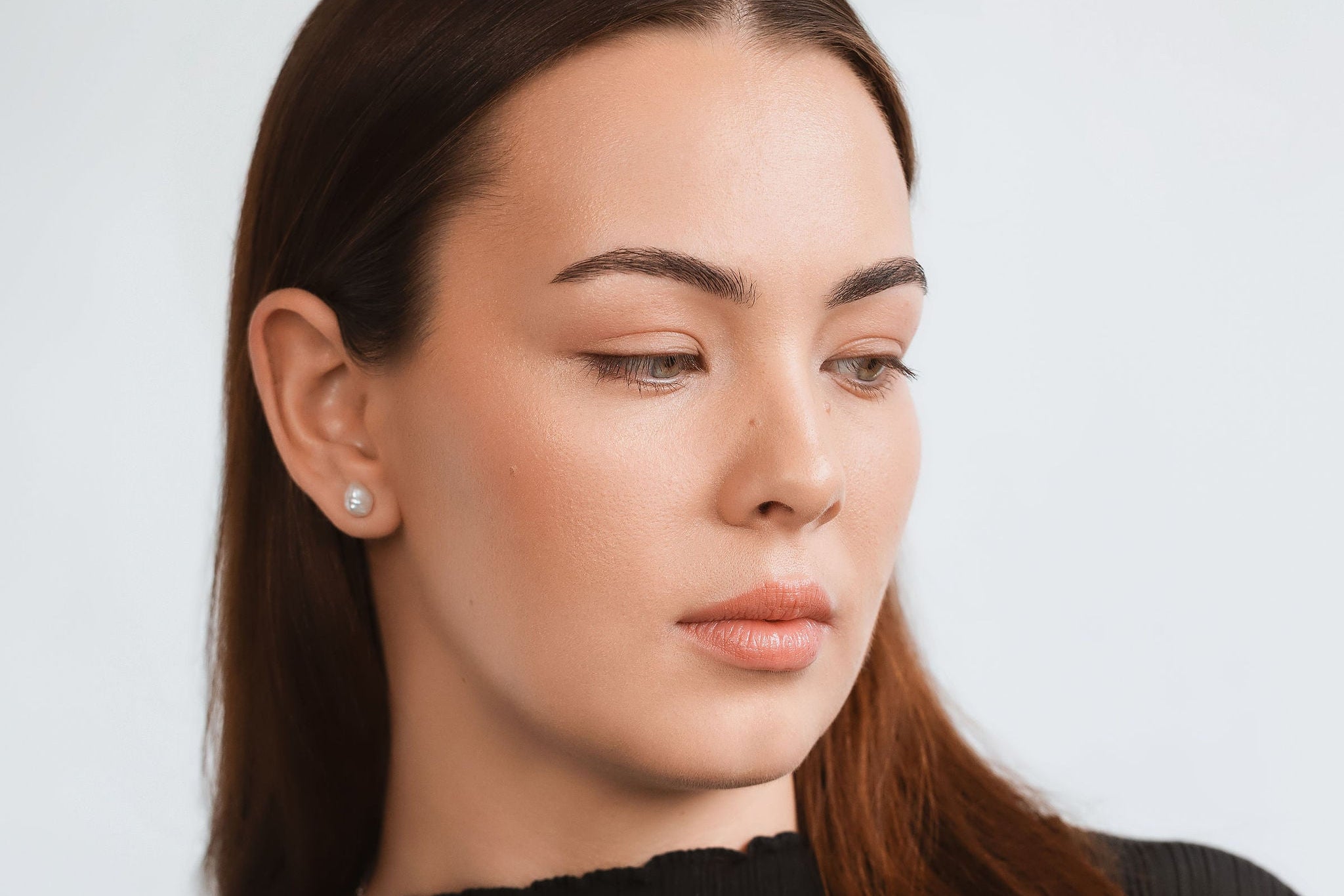 Woman wearing a silver necklace against a plain background