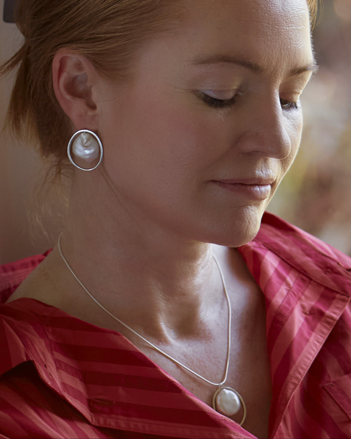 A woman wearing sterling silver stud earrings with freshwater pearls.