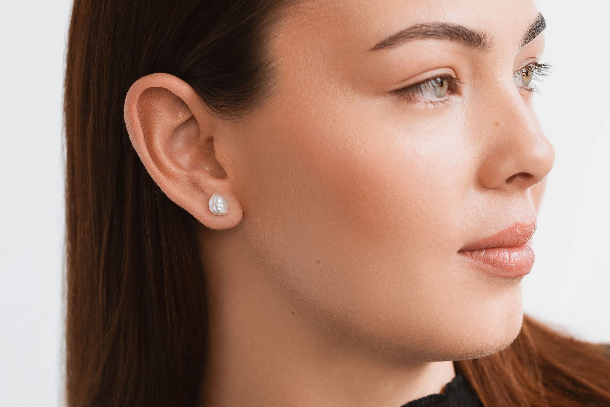 Woman wearing a pearl earring against a white background